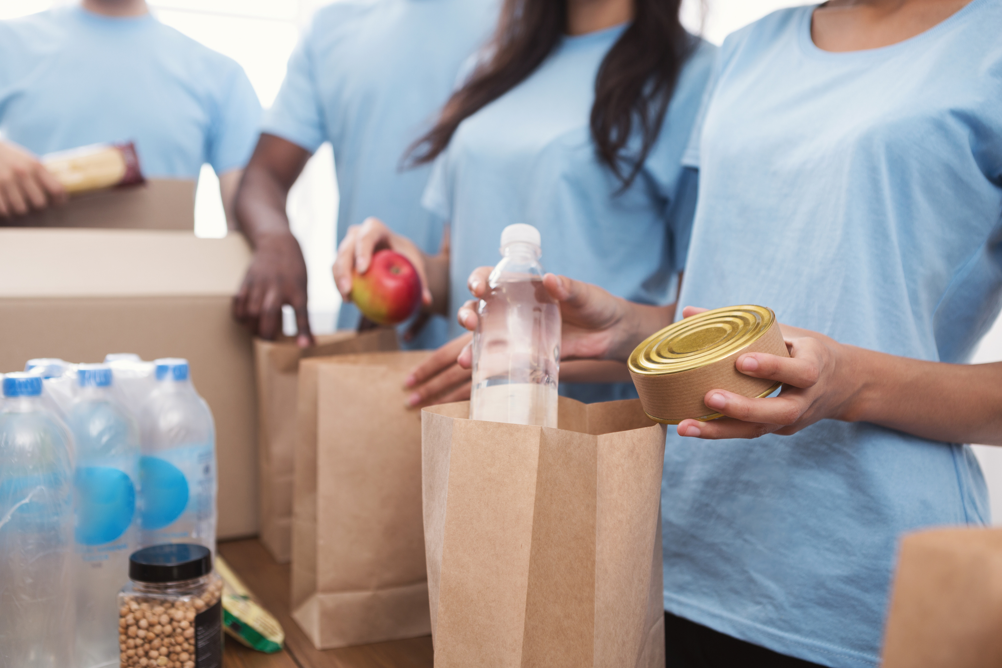 Volunteers packing food and drinks into paper bags